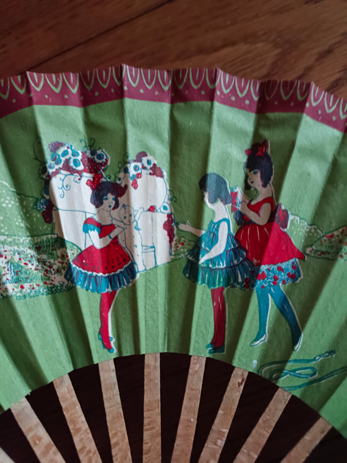 Éventail en papier et bois vers 1930 à décor de jeunes filles dans un décor bucolique