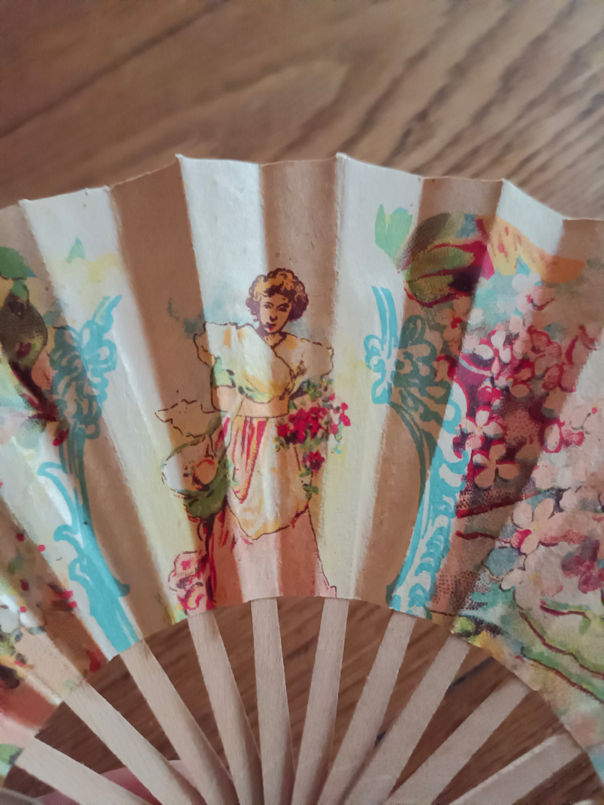 Petit éventail en papier et bois vers 1930 à décor de jeune femme au bouquet
